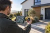 Un propriétaire compare une carte satellite générique et une boussole devant sa maison.