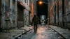 Homme en hoodie courant seul dans une ruelle urbaine sombre la nuit