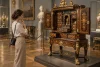 Une visiteuse observe un cabinet russe richement marqueté dans une galerie de musée.