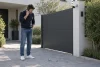 Un propriétaire observe des cailloux inhabituels près de son portail en téléphonant.