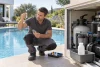 Professionnel inspectant l’eau et le circuit de filtration fermé d’une piscine.