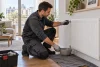 Technicien ganté préparant la purge prudente d’un radiateur dans un appartement.